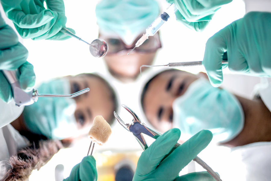 Masked dental professionals looking down on the patient prior to oral surgery.