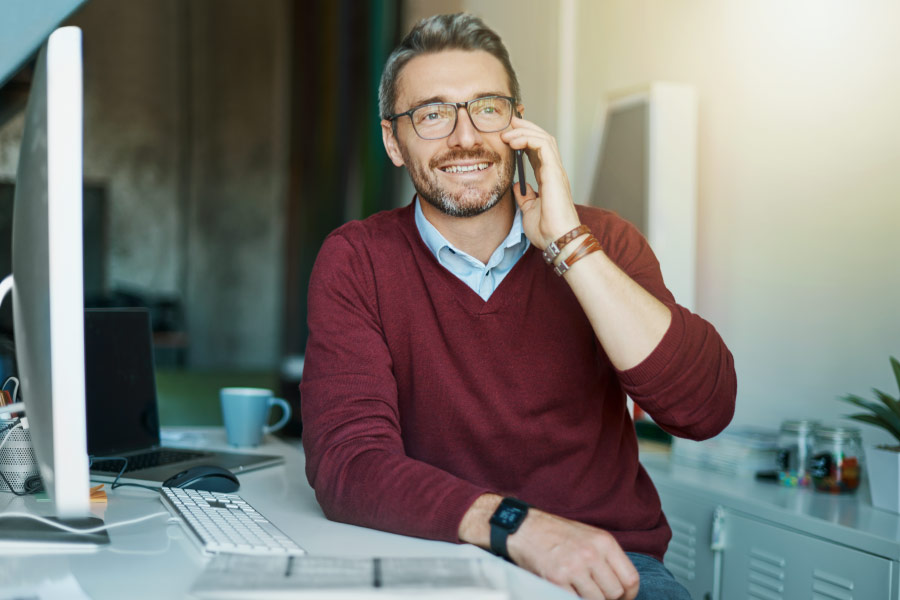 Man working at a computer and talking on the phone.