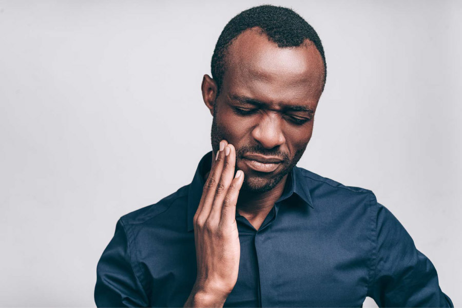 Man holding his hand to his cheek due to a tooth abscess.