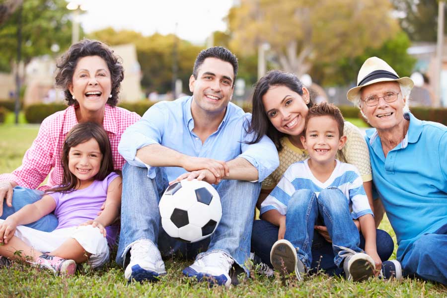 Multi-generational hispanic family sitting outside together with a soccer ball.