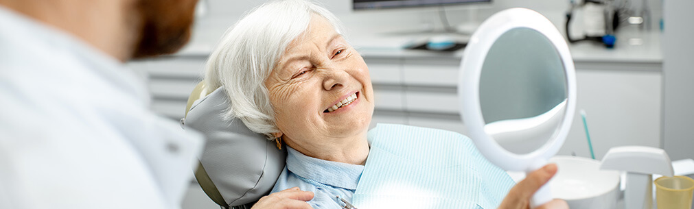 senior woman looking at her smile in a mirror