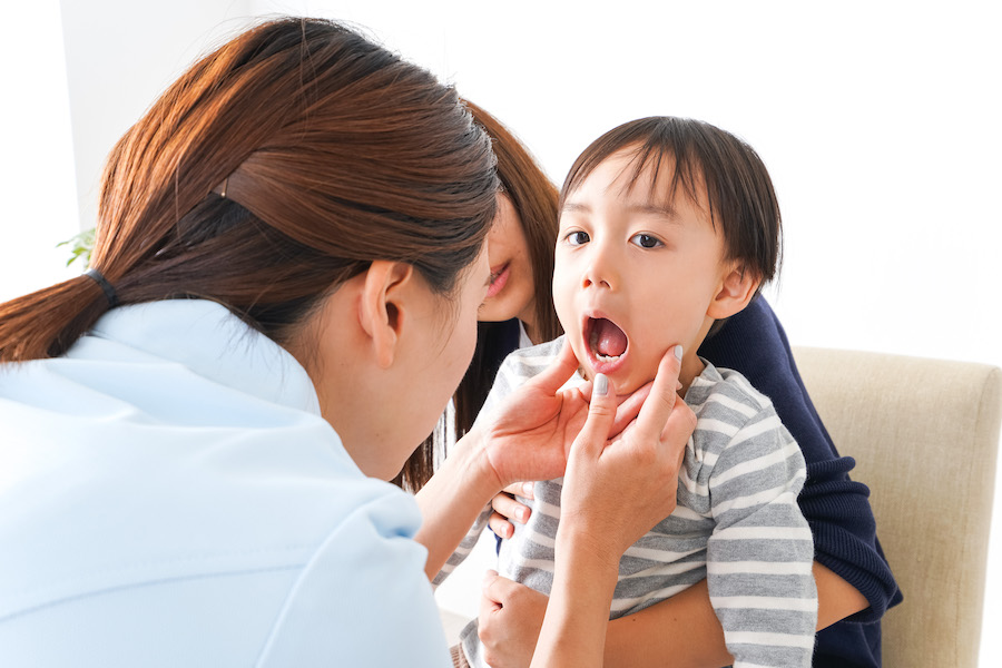 A dentist examines the open mouth of a young brunette child
