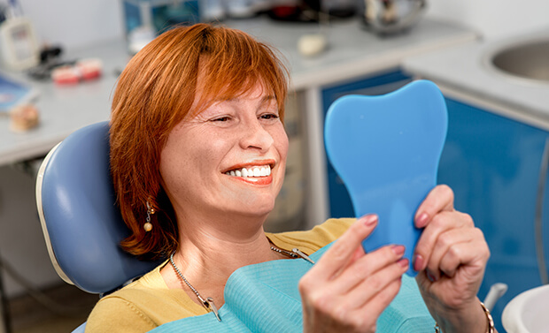 woman examining her smile in a mirror