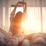 Woman waking up after resting, emphasizing the importance of rest as part of tooth extraction aftercare.