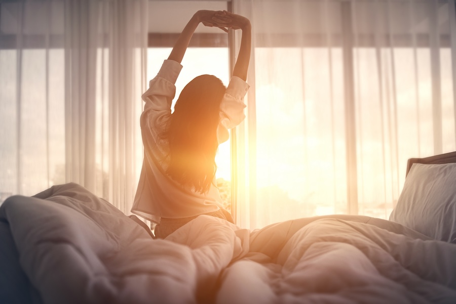 Woman waking up after resting, emphasizing the importance of rest as part of tooth extraction aftercare.